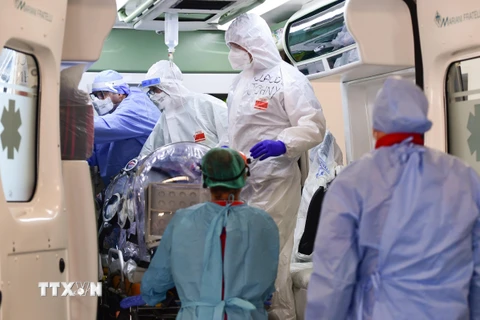 Nhân viên y tế chuyển bệnh nhân nhiễm COVID-19 tới bệnh viện ở Milan, Italy. (Ảnh: AFP/TTXVN)