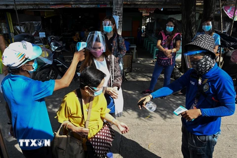 Đo thân nhiệt nhằm ngăn chặn sự lây lan của dịch COVID-19 trước khi lên xe buýt ở Manila, Philippines. (Ảnh: AFP/TTXVN)