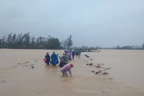 Người dân cố di chuyển trên một đoạn đường ngập nước do mưa lũ. (Nguồn: tuoitre.vn)