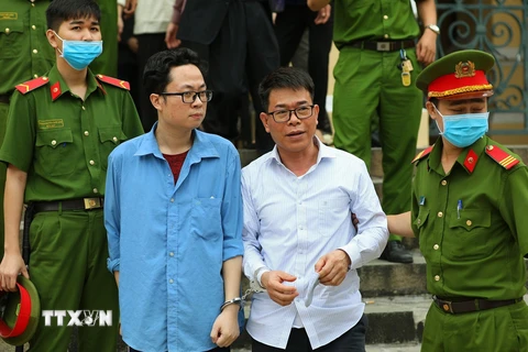 Bị cáo Lâm Hoàng Tùng (áo xanh), bị cáo Nguyễn Hải Nam (áo trắng) sau phiên tòa ngày 30/12/2020. (Ảnh: TTXVN phát)