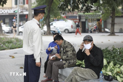 Nhân viên Ban quản lý khu vực hồ Hoàn Kiếm nhắc nhở người dân đeo khẩu trang nơi công cộng. (Ảnh: Minh Quyết/TTXVN)