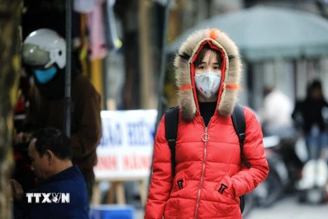 Người dân ra đường mặc áo ấm kín mít, đeo khẩu trang để chống lại giá rét. (Ảnh: Thành Đạt/TTXVN)