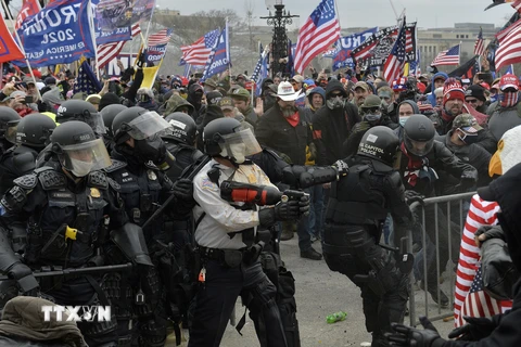 Người biểu tình xung đột với cảnh sát chống bạo động tại Đồi Capitol ở Washington DC., ngày 6/1/2021. (Ảnh: AFP/TTXVN)