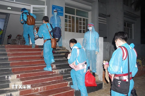 Công dân Việt Nam từ nước ngoài trở về được các nhân viên y tế hướng dẫn vào khu cách ly. (Ảnh: Chanh Đa/TTXVN)