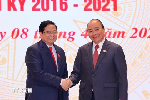 Chủ tịch nước Nguyễn Xuân Phúc, nguyên Thủ tướng Chính phủ chúc mừng Thủ tướng Chính phủ Phạm Minh Chính. (Ảnh: TTXVN)