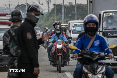 Cảnh sát gác tại một chốt kiểm soát để nhắc nhở người dân thực hiện tốt các biện pháp phòng dịch COVID-19 ở Quezon, ngoại ô Manila, Philippines. (Ảnh: AFP/TTXVN)