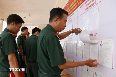 Các chiến sỹ thuộc Bộ Chỉ huy Quân sự tỉnh Cà Mau theo dõi danh sách cử tri được niêm yết tại đơn vị. (Ảnh: Kim Há/TTXVN)