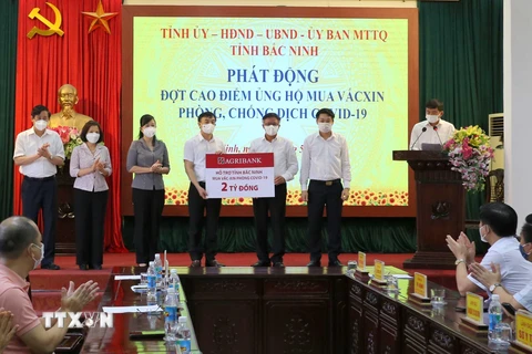 Đại diện lãnh đạo tỉnh Bắc Ninh tiếp nhận 2 tỷ đồng của Ngân hàng Nông nghiệp và Phát triển nông thôn chi nhánh Bắc Ninh. (Ảnh: Thái Hùng/TTXVN)