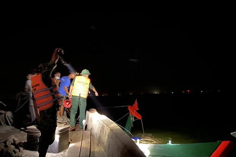 Lực lượng chức năng cùng người dân kéo tàu cá gặp nạn vào bờ. (Nguồn: plo.vn)