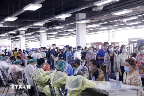 Các nhân viên y tế tại một điểm tiêm ở thủ đô Vientiane cấp thẻ tiêm cho những người tiêm vaccine mũi 1. (Ảnh: Phạm Kiên/TTXVN)