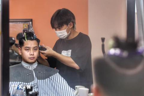 Các cửa hàng cắt tóc mỗi lượt chỉ nhận từ 1 đến 2 khách, để đảm bảo việc giãn cách phòng dịch COVID-19. (Ảnh: Tuấn Đức/TTXVN)