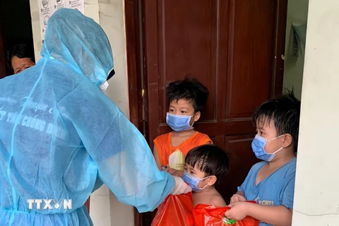 Các thanh niên tình nguyện trao quà Tết thiếu nhi cho các trẻ em trong khu cách ly tại Thuận An (Bình Dương). (Ảnh: TTXVN phát)