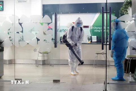 Lực lượng chức năng phun thuốc khử khuẩn trụ sở Ngân hàng Vietcombank, thành phố Thái Nguyên nơi liên quan đến một bệnh nhân COVID-19. (Ảnh: Trần Trang- TTXVN)