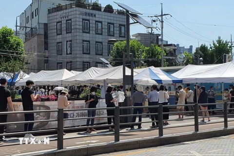 Người dân xếp hàng xét nghiệm COVID-19 trong thời tiết nắng nóng ở quận Seongbuk, Seoul. (Ảnh: Mạnh Hùng/TTXVN)