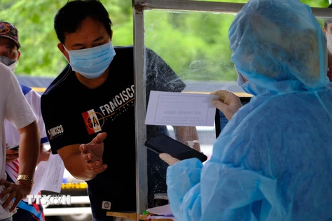 Lực lượng y tế kiểm tra lại thông tin của một tài xế tại khu vực khai báo y tế, xuất trình các giấy tờ liên qua khi đi qua trạm kiểm soát COVID-19 trên quốc lộ 20, tỉnh Lâm Đồng. (Ảnh: Nguyễn Dũng - TTXVN)