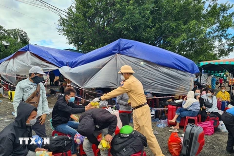 Lực lượng chức năng tỉnh Gia Lai cấp xăng, nước uống và xôi cho người dân từ vùng dịch về quê khi đi ngang qua chốt kiểm dịch Cầu 110 (xã Ia Le, huyện Chư Pưh). (Ảnh: TTXVN phát)