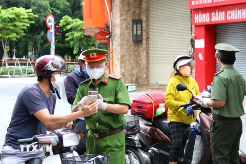 Lực lượng chức năng kiểm tra người dân thực hiện khai báo thông tin di biến động trên đường Võ Thị Sáu, quận 3, Thành phố Hồ Chí Minh. (Ảnh: Thanh Vũ/TTXVN)