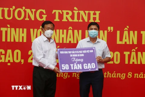 Ông Nguyễn Tiếc Hùng, Chủ tịch Ủy ban Mặt trận Tổ quốc Việt Nam tỉnh An Giang (trái), tiếp nhận bằng tượng trưng hỗ trợ từ các nhà hảo tâm. (Ảnh: Công Mạo/TTXVN)