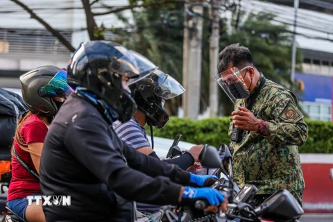 Cảnh sát kiểm tra nhắc nhở người dân thực hiện các biện pháp phòng dịch COVID-19 tại một chốt kiểm soát ở Quezon, Philippines. (Ảnh: THX/TTXVN)