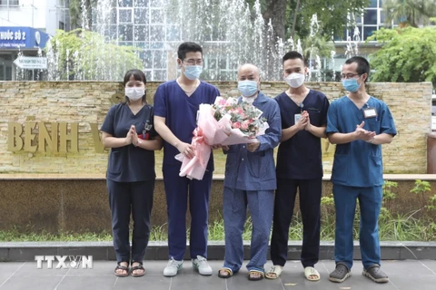 Êkíp bác sỹ, điều dưỡng điều trị ca bệnh của Bệnh viện Thanh Nhàn tặng hoa chúc mừng bệnh nhân H.V.N (giữa) khỏi bệnh, ra viện ngày 17/9. (Ảnh: Minh Quyết/TTXVN)