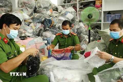Lực lượng chức năng kiểm đếm các sản phẩm quần áo, túi sách không rõ nguồn gốc, nhập lậu tại cơ sở kinh doanh Trần Lan. (Ảnh: TTXVN phát)