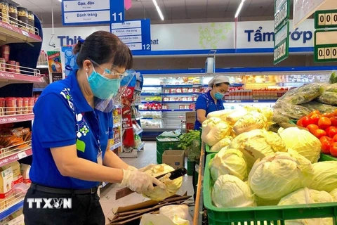Nhân viên siêu thị Thành phố Hồ Chí Minh bổ sung hàng hóa lên kệ phục vụ khách hàng mua sắm trực tiếp. (Ảnh: TTXVN phát)