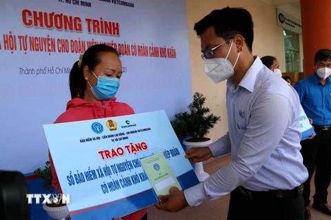  Lãnh đạo Quận ủy quận Tân Phú trao sổ bảo hiểm cho đoàn viên nghiệp đoàn có hoàn cảnh khó khăn ở quận Tân Phú. (Ảnh: Thanh Vũ/TTXVN)