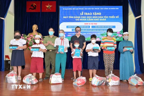 Đại diện các nhà hảo tâm trao tặng máy tính bảng và quà cho một số học sinh người Khmer và Chăm có hoàn cảnh khó khăn. (Ảnh: Xuân Khu/TTXVN)