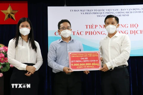Ông Phạm Minh Tuấn, Phó Chủ tịch Ủy ban MTTQ Việt Nam Thành phố Hồ Chí Minh (giữa) tiếp nhận tượng trưng kinh phí ủng hộ công tác phòng, chống dịch từ Tổng Công ty Điện lực Thành phố Hồ Chí Minh. (Ảnh: Xuân Khu/TTXVN)