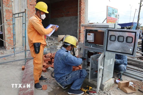 Nhân viên điện lực lắp điện kế cho người dân Khu tái định cư Lộc An-Bình Sơn. (Ảnh: Công Phong/TTXVN)