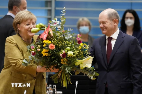 Ông Olaf Scholz tặng hoa cho Thủ tướng sắp mãn nhiệm Angela Merkel trước cuộc họp nội các ở Berlin, Đức, ngày 24/11/2021. (Ảnh: AFP/TXVN)
