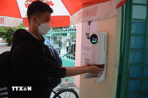 Học sinh lớp 8, 9 trường Trung học cơ sở Hoàng Sa (quận Thọ Quang) đo thân nhiệt và rửa tay bằng nước sát khuẩn tại cổng trường. (Ảnh: Văn Dũng/TTXVN)