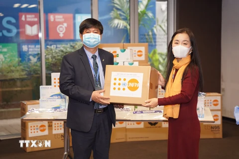 Bà Naomi Kitahara, Trưởng đại diện UNFPA tại Việt Nam, trao tượng trưng số thiết bị và vật tư y tế phòng, chống dịch COVID-19 cho ông Đinh Anh Tuấn, Phó Vụ trưởng Vụ Chăm sóc Sức khỏe Bà mẹ và Trẻ em (Bộ Y tế). (Ảnh: TTXVN phát)