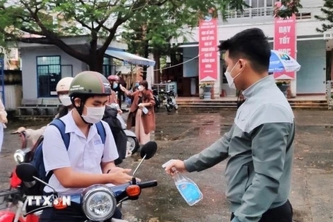 Học sinh trường THPT Hoàng Hoa Thám (Hà Nội) xịt khử khuẩn tại cổng trường. (Ảnh: Văn Dũng/TTXVN)