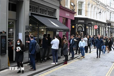 Người dân xếp hàng mua đồ bên ngoài một cửa hàng ở London (Anh), ngày 29/4/2021. (Ảnh: AFP/TTXVN)