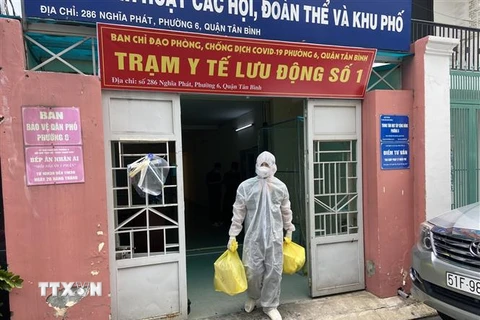 Lực lượng Quân y tại Trạm y tế lưu động số 1 (phường 6, quận Tân Bình) mang các đồ dùng cần thiết (bình oxy, máy đo nồng độ oxy, ống nghe, nhiệt kế, dung dịch sát khuẩn, khẩu trang…) đến nhà F0. (Ảnh: Mạnh Linh/TTXVN)