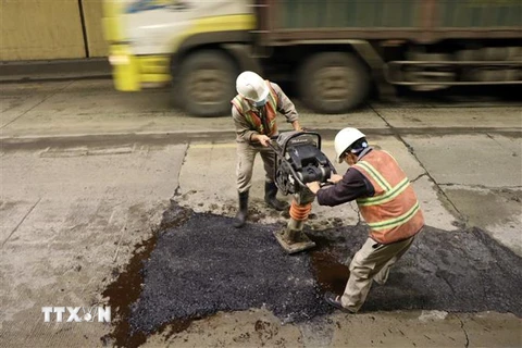 Đơn vị quản lý hầm xử lý gia cố tạm thời những vị trí nền đường bị hư hỏng bằng thảm nhựa đường ngày 13/1. (Ảnh: Đỗ Trưởng/TTXVN)