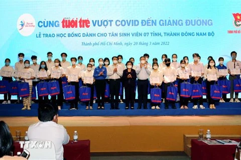 Đại diện Ban tổ chức với các tân sinh viên, học sinh Thành phố Hồ Chí Minh và các tỉnh miền Đông Nam bộ nhận học bổng “Tiếp sức đến trường” năm học 2021-2022. (Ảnh: Thanh Vũ/TTXVN)