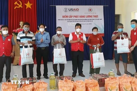 Đại diện Hội Chữ thập đỏ Việt Nam và chính quyền địa phương trao nhu yếu phẩm cho các hộ dân. (Ảnh: TTXVN phát)