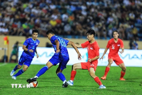 Weerathep Pomphun (18) của U23 Thái Lan nỗ lực đi bóng trước sự truy cản của cầu thủ U23 Singapore. (Ảnh: Tuấn Anh/TTXVN)