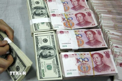 Đồng USD và đồng nhân dân tệ tại một ngân hàng ở tỉnh An Huy, Trung Quốc. (Ảnh: AFP/TTXVN)