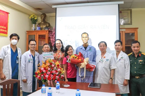 PGS.TS-Bác sỹ Chuyên khoa II Trương Đình Cẩm, Phó Giám đốc Bệnh viện Quân y 175 trao giấy ra viện, tặng hoa chúc mừng bệnh nhân khỏi bệnh. (Nguồn: benhvien175.vn)