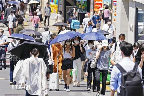 Người dân che ô tránh nắng nóng khi di chuyển trên đường phố tại Tokyo, Nhật Bản, ngày 28/6/2022. (Ảnh: Kyodo/TTXVN)