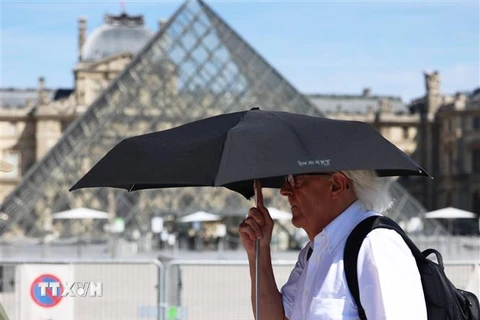 Người dân che ô bảo vệ trong thời tiết nắng nóng tại Paris, Pháp. (Ảnh: THX/TTXVN)