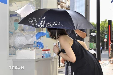 Người dân lấy mẫu xét nghiệm COVID-19 trong tiết trời nắng nóng tại Thượng Hải, Trung Quốc ngày 13/7/2022. (Ảnh: Kyodo/TTXVN)