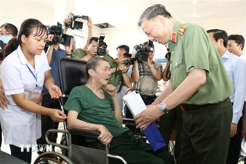 Đại tướng Tô Lâm thăm hỏi sức khỏe và trao quà tặng một đồng chí thương binh nặng đang điều dưỡng tại Trung tâm. (Ảnh: Đức Phương/TTXVN)