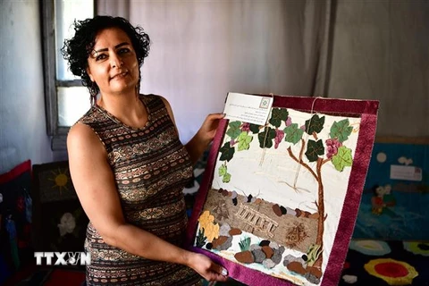 Cô Manal Masoud giới thiệu tác phẩm nghệ thuật từ vải cũ tại Sweida, Syria. (Ảnh: THX/TTXVN)
