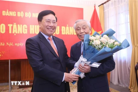 Phó Thủ tướng Thường trực Phạm Bình Minh tặng hoa, chúc mừng Nguyên Phó Thủ tướng Nguyễn Mạnh Cầm nhận Huy hiệu 75 năm tuổi Đảng. (Ảnh: Lâm Khánh/TTXVN)