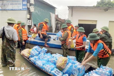 Lực lượng chức năng vận chuyển lương thực, nước uống hỗ trợ người dân vùng bị ngập tại huyện Quỳnh Lưu (Nghệ An). (Ảnh: Tá Chuyên/TTXVN)