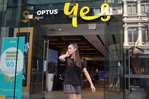 Một phụ nữ sử dụng điện thoại di động khi đi ngang qua cửa hàng Optus ở Sydney, Australia. (Nguồn: Reuters)